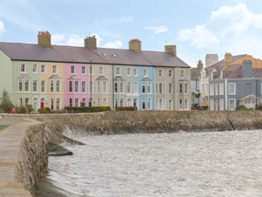 A row of colorful terraced houses by a rocky shoreline. - Little House (Beaumaris)