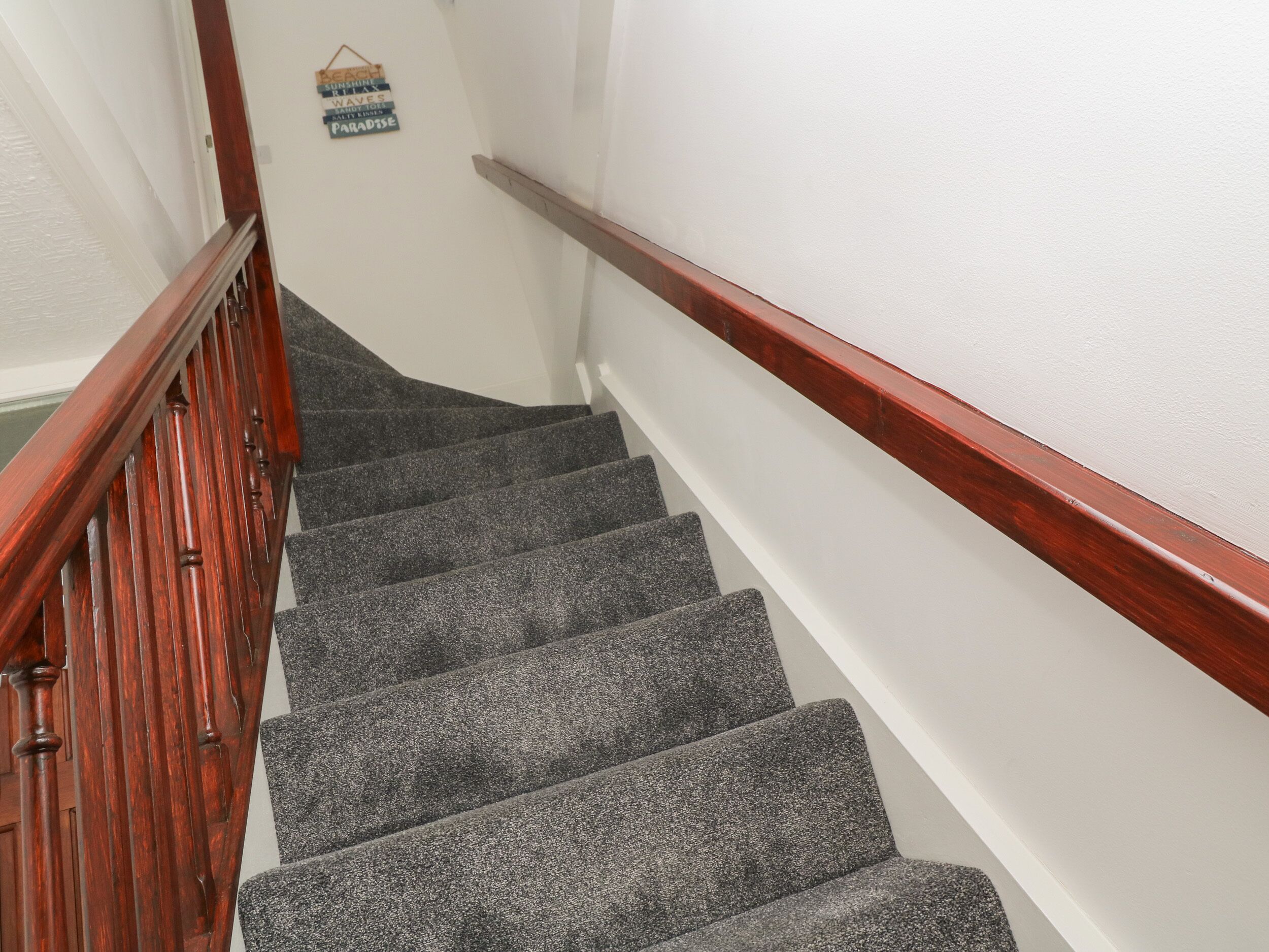 A staircase with wooden handrails and carpeted steps.