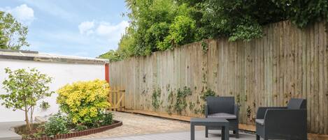 A wooden deck with outdoor furniture and a garden area with yellow flowers.