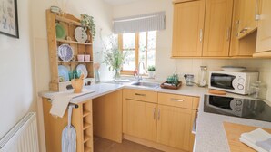A kitchen with wooden cabinets, a sink, a microwave, and a stove.