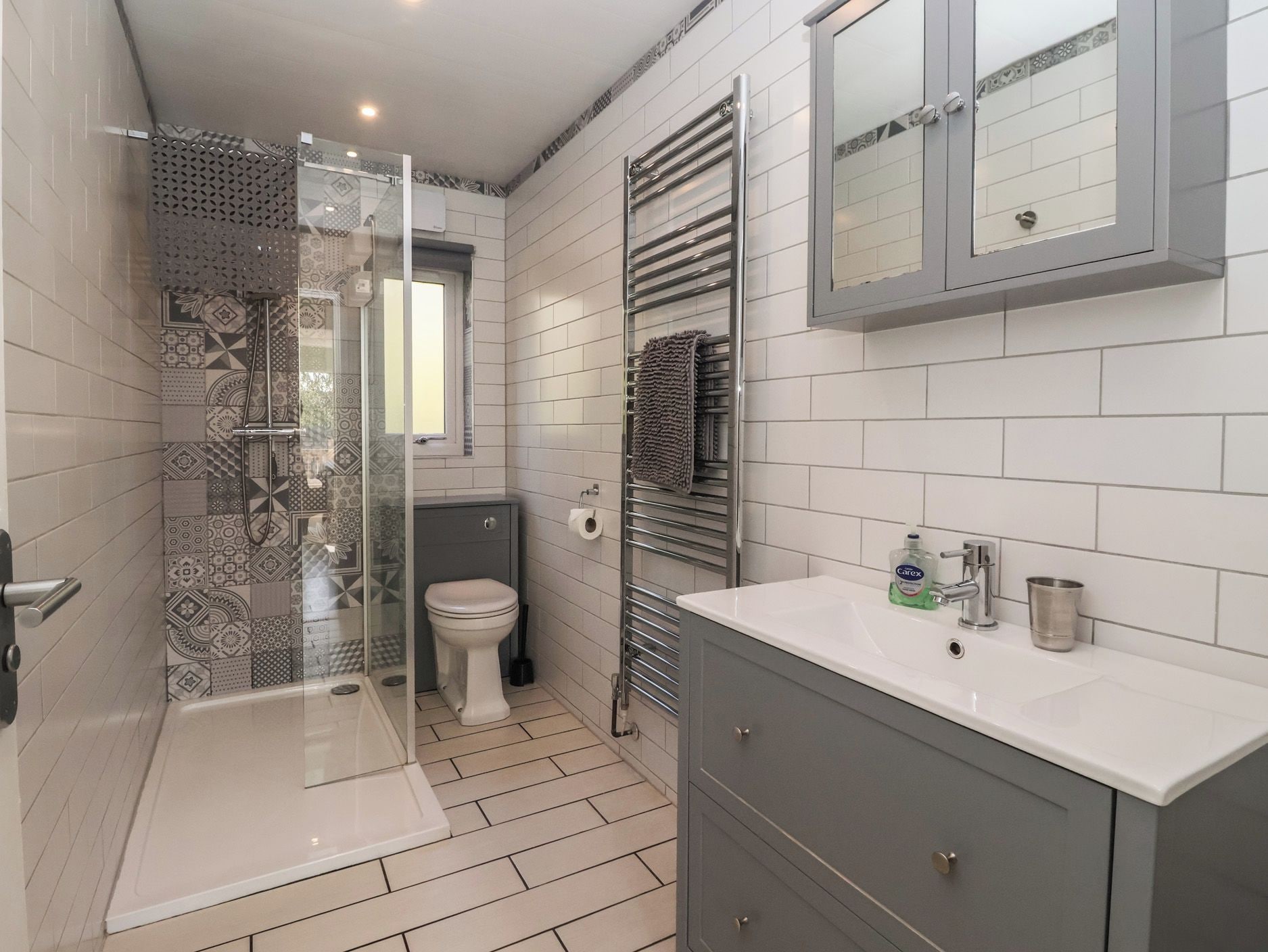 Un baño moderno con ducha, inodoro, tocador y zona de ducha con mampara de vidrio.