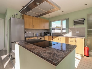 Una cocina moderna con encimeras de granito, electrodomésticos de acero inoxidable y armarios de madera.