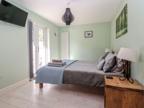 Un dormitorio con cama, mesita de noche, lámpara y una obra de arte en la pared.