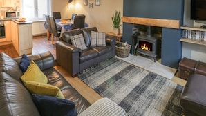 A modern living room with a fireplace, leather sofas, a dining area, and a kitchen. - Mulgrave Cottage (Saltburn-by-the-Sea)