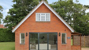 A red brick building with a gabled roof, large sliding glass doors, and a small patio area. - Thames Reach (Wallingford)