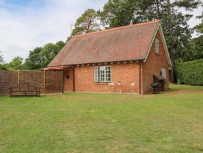 A brick house with a tiled roof, a fenced yard, and a bench. - Thames Reach (Wallingford)