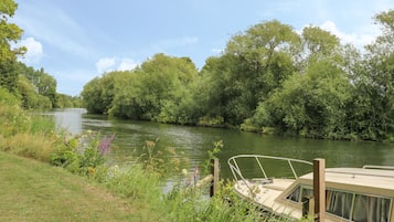 A river with a boat docked on the right, surrounded by lush greenery and trees.