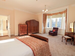 A bedroom with a large bed, a wooden wardrobe, a chair, and a dresser. - Auchentroig House (Glasgow)