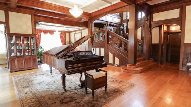 Un piano de cola en una habitación amplia con piso de madera y un tapete grande.