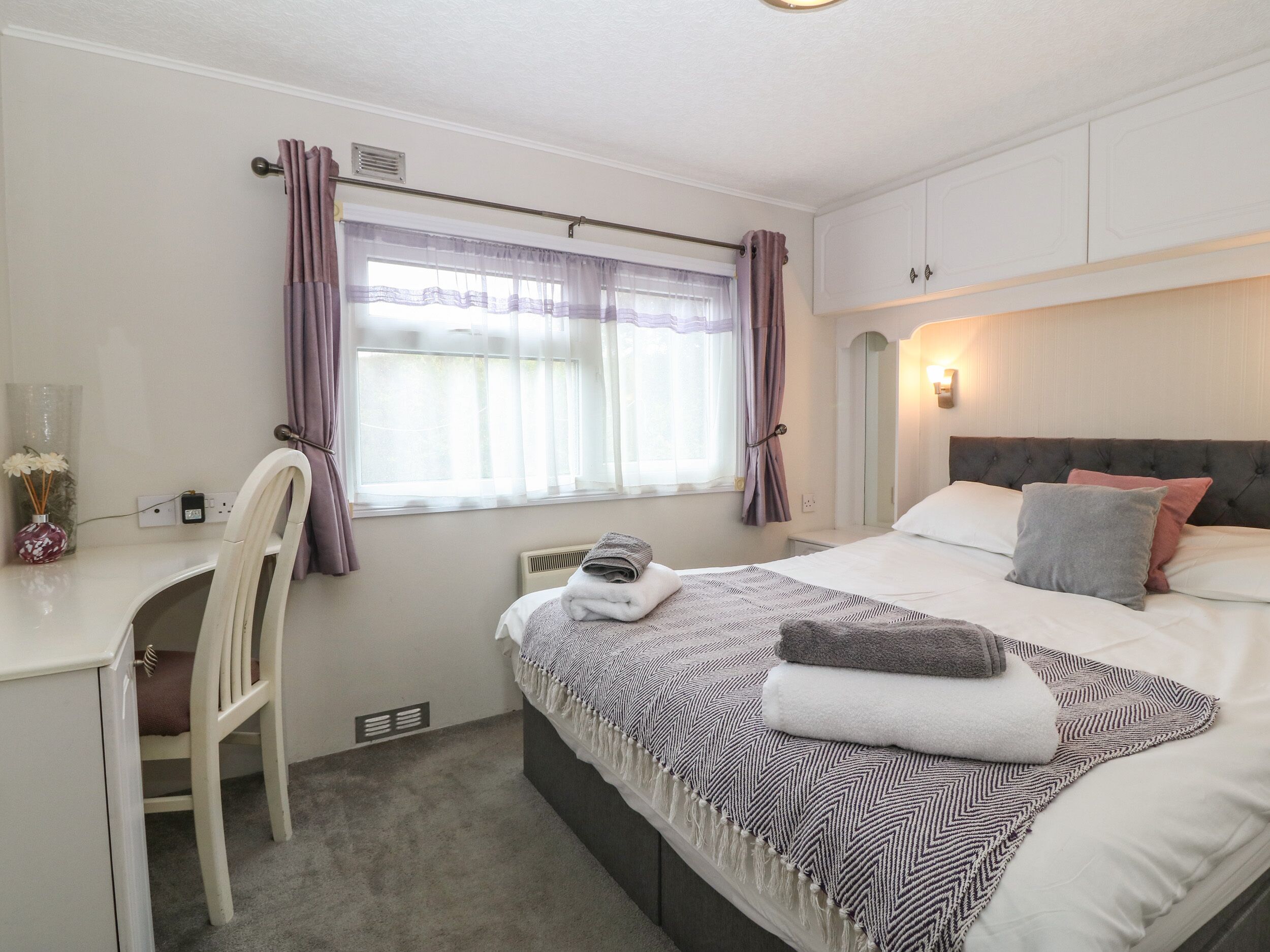 A bedroom with a bed, a desk, and a chair.