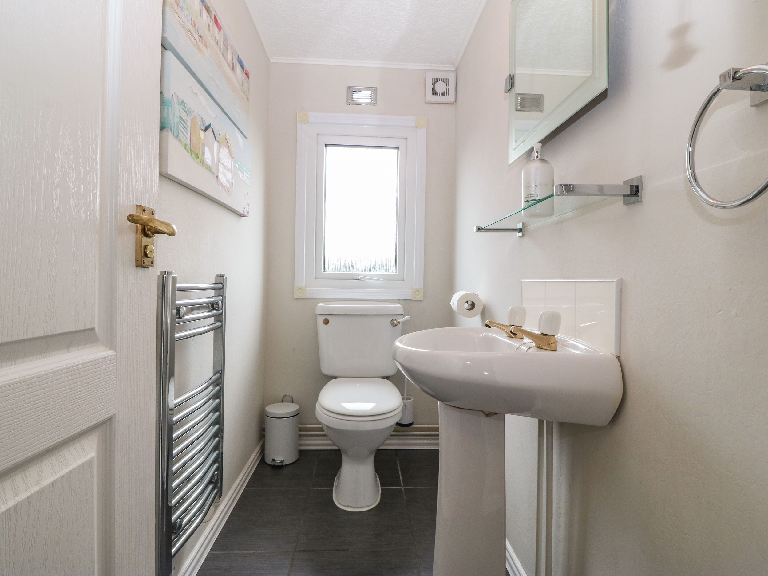 A compact bathroom with a toilet, sink, and a window above the toilet.