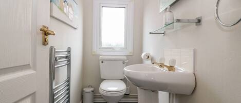A compact bathroom with a toilet, sink, and a window above the toilet.