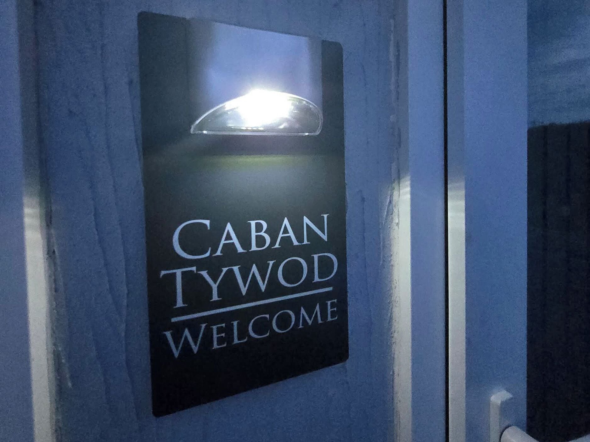En skylt med texten ”CABAN TYWOD WELCOME” på en blå bakgrund.