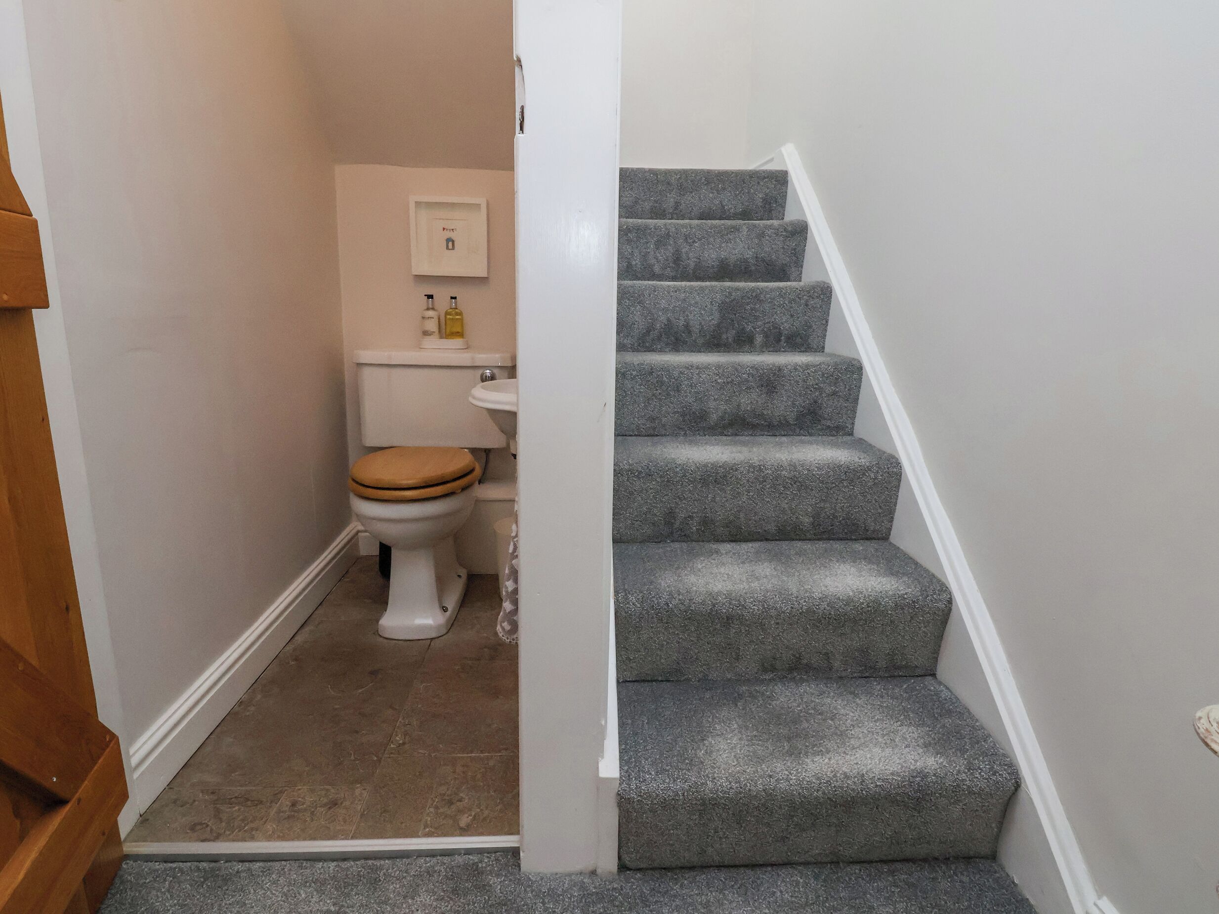 Un baño con inodoro, lavamanos y una escalera que sube a otro piso.