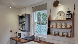 Una cocina con microondas, lavamanos y encimera de madera.