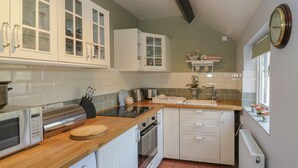 Eine kompakte Küche mit weißen Schränken, einer Holz Arbeitsplatte, einer Bosch Waschmaschine und einem eingebauten Backofen.