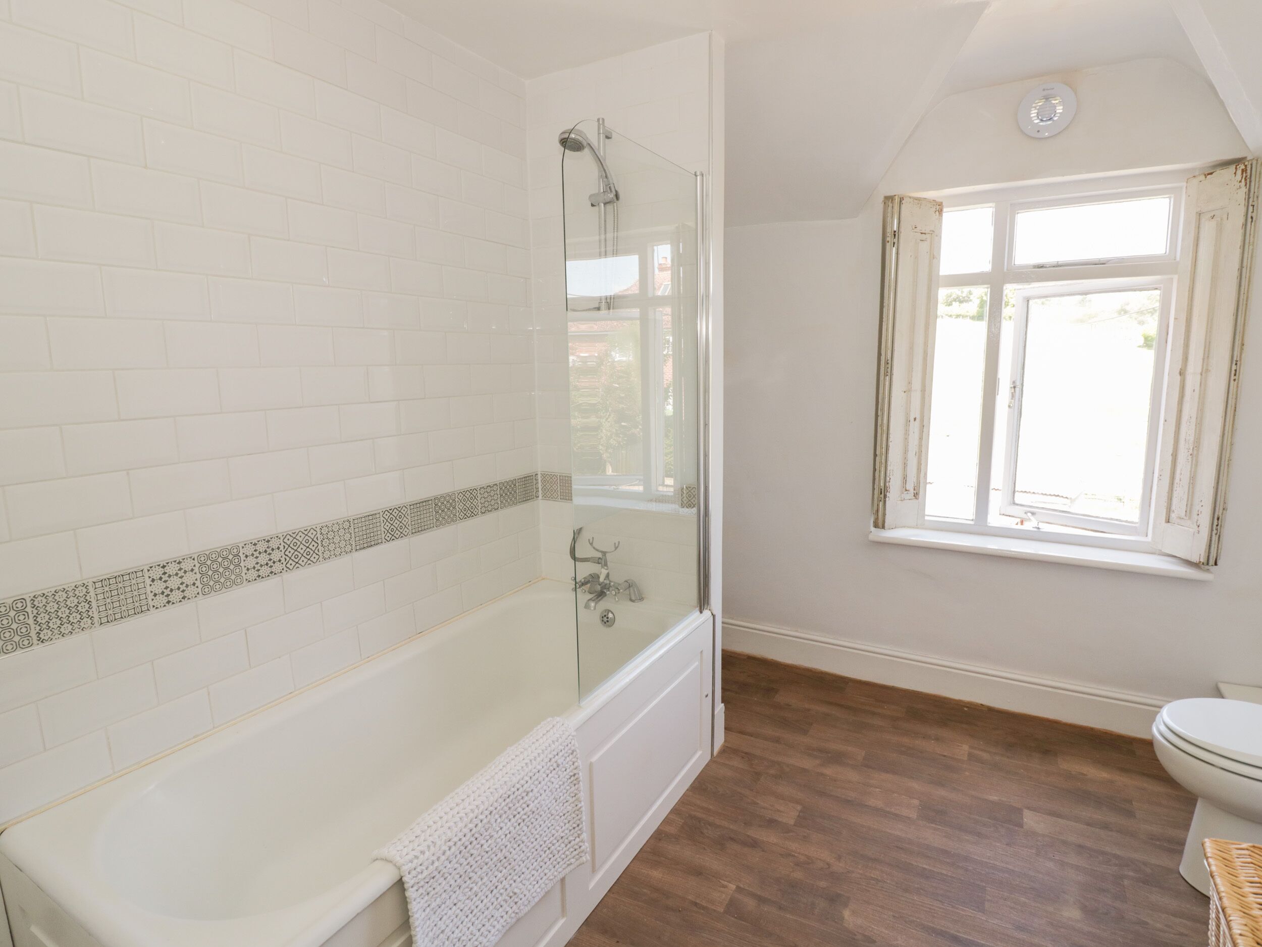 A bathroom with a bathtub, a shower, a toilet, and a window.