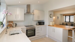 Una cocina moderna con armarios blancos, extractor de acero inoxidable, horno empotrado y una mesa de comedor de madera.