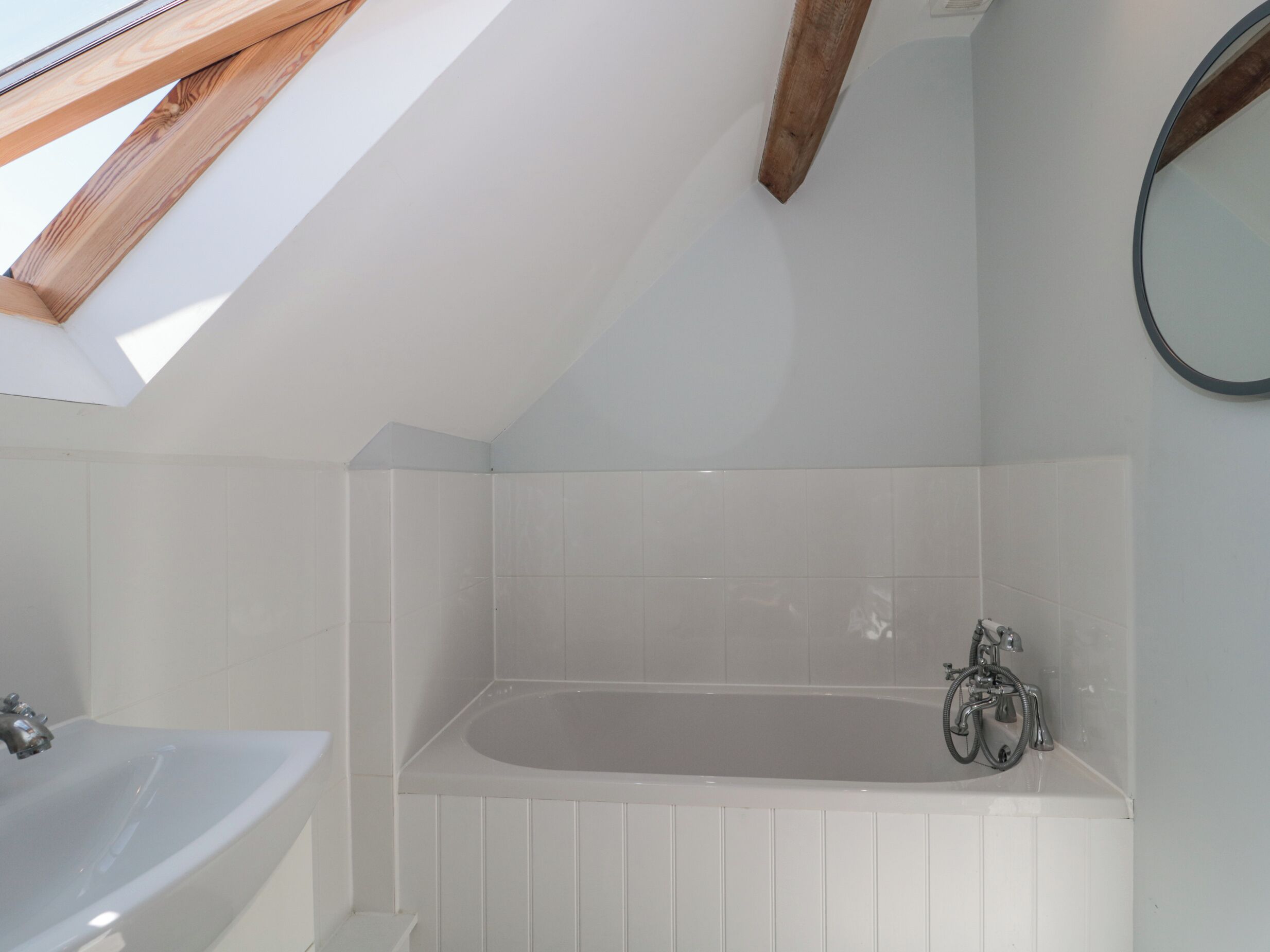 A modern bathroom with a skylight, a bathtub, and a sink.
