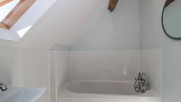 A modern bathroom with a skylight, a bathtub, and a sink.