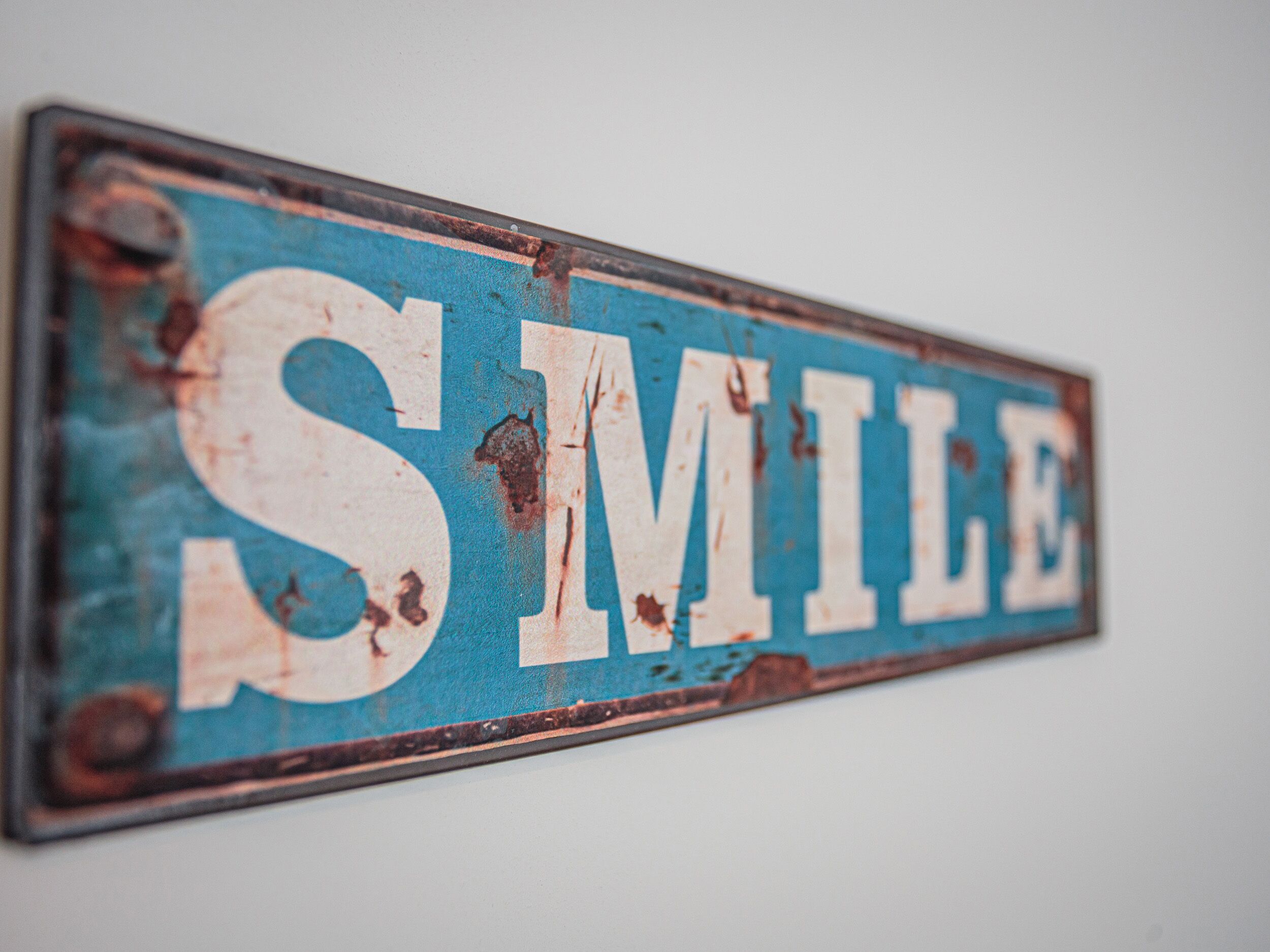 Un letrero de metal desgastado con la palabra 'SMILE' en letras grandes.