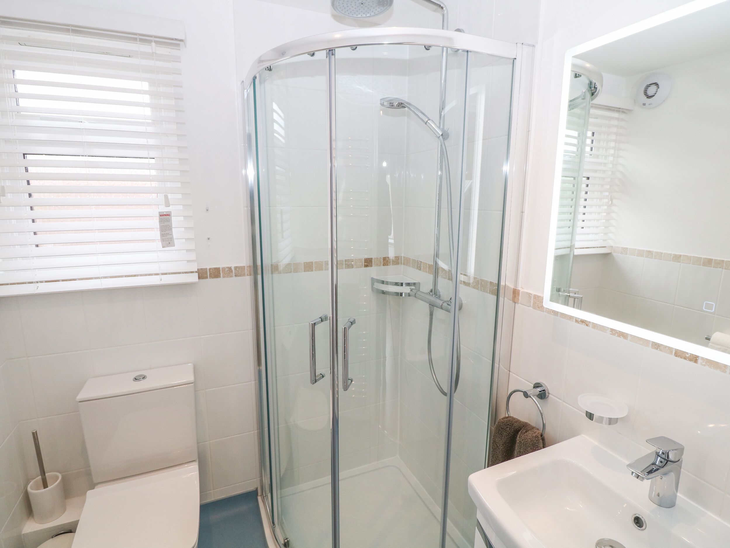 A modern bathroom with a glass-enclosed shower, a toilet, and a sink with a mirror.
