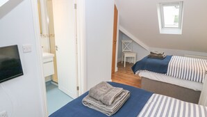 Un dormitorio con dos camas, un televisor, una mesita y una ventana.