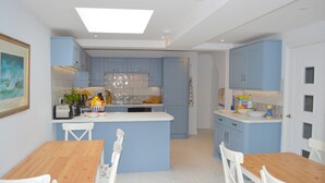 Una cocina moderna con armarios azules, una isla central y sillas blancas.