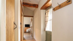 A hallway with wooden floors, a green door, and a television in the background. - Sunrise Stable (Spalding)