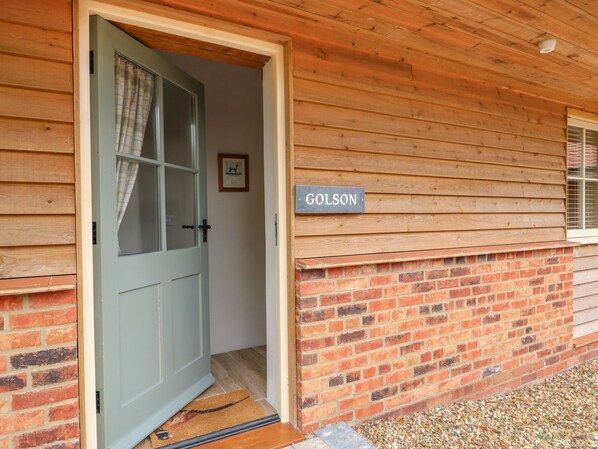 A wooden building with a sign reading "GOLSON" and a door leading inside. - Golson Stable (Spalding)