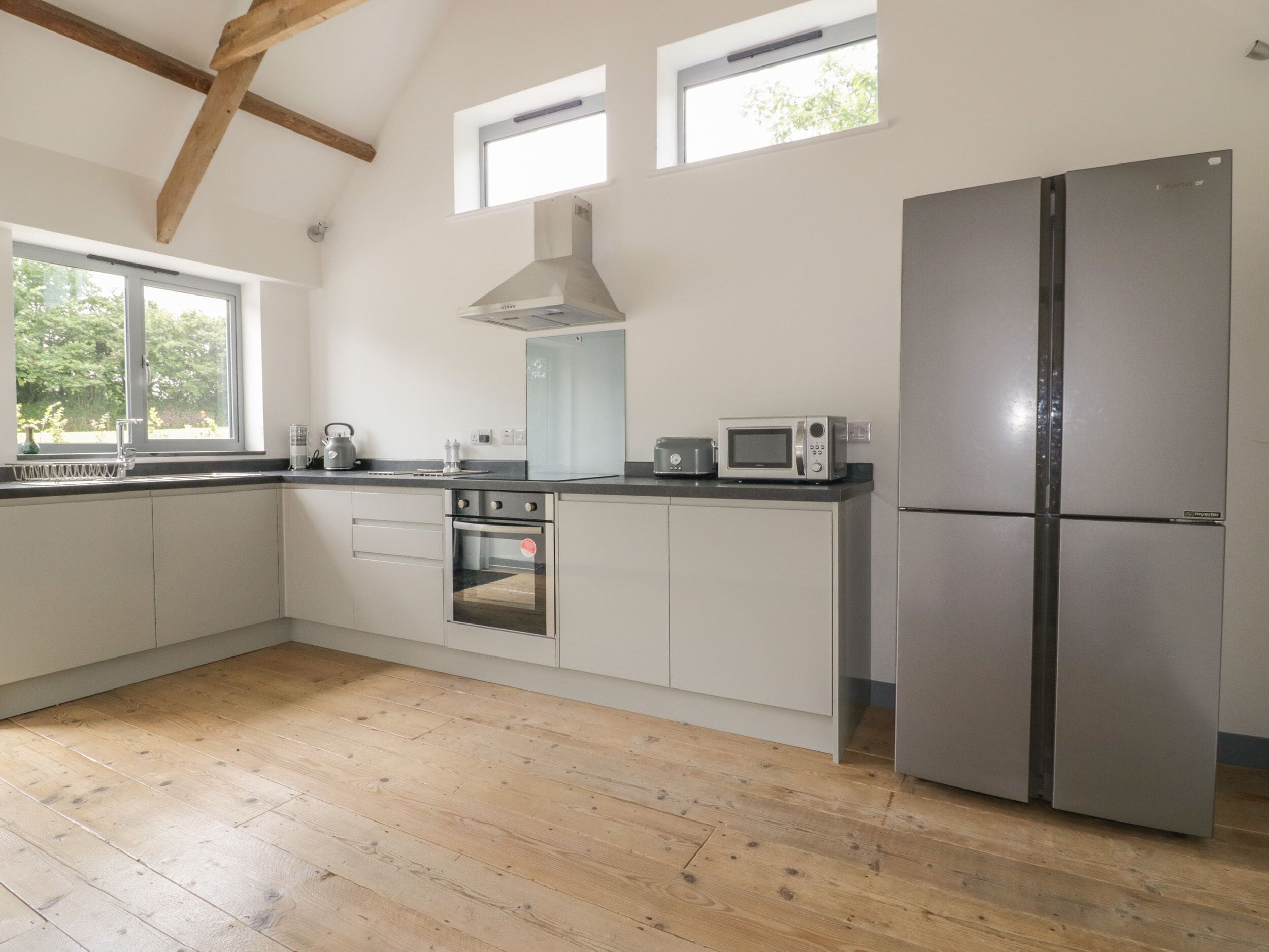 A modern kitchen with white cabinets, a stainless steel refrigerator, a microwave, and a kettle on the counter.