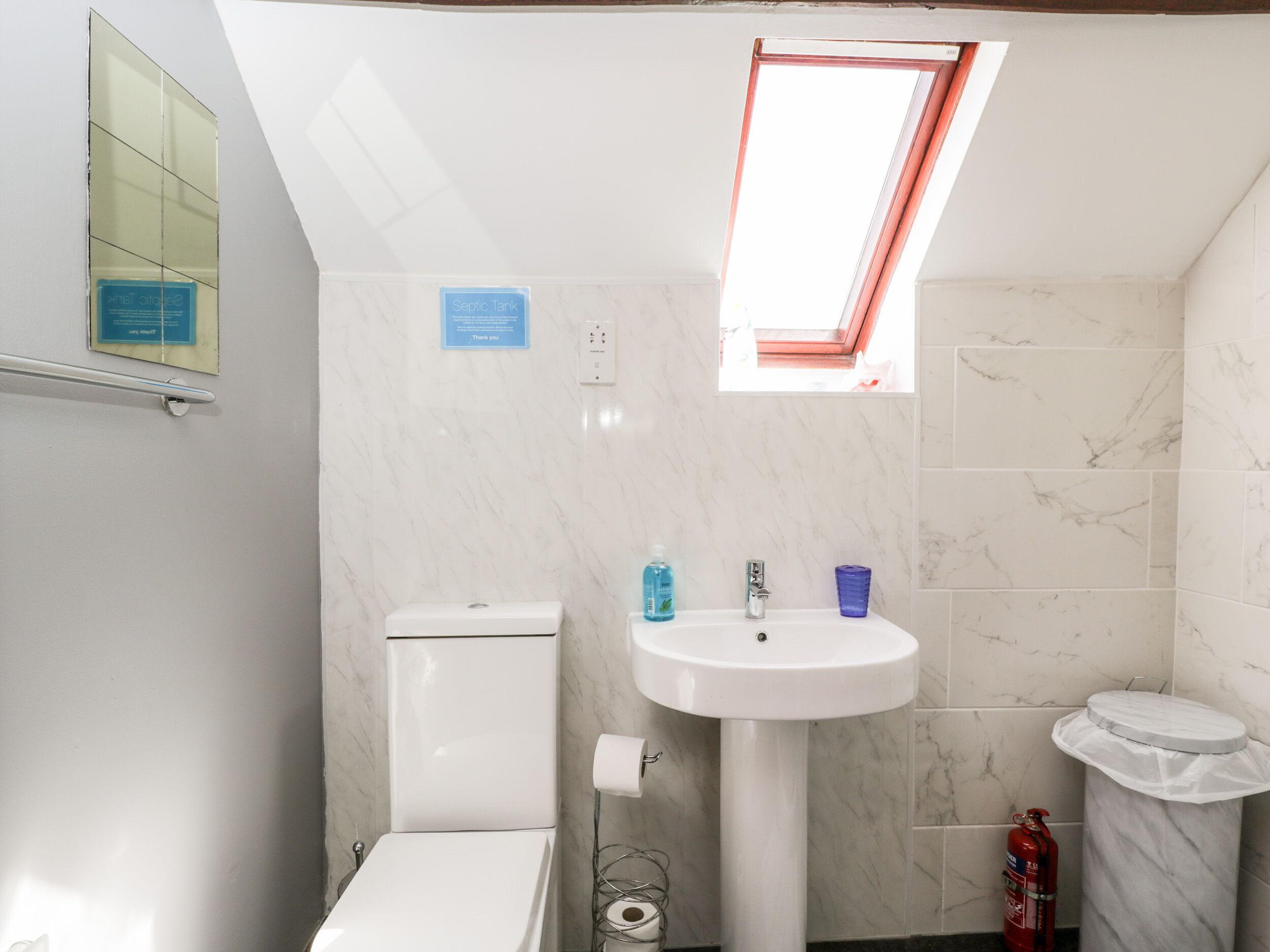 A bathroom with a toilet, sink, and a window.