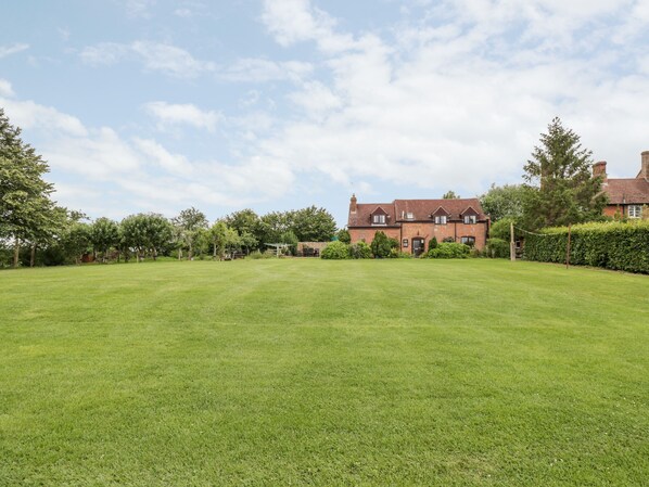 A large, open grassy lawn with a brick house in the background.