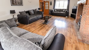 A spacious living room with two sofas, a coffee table, and a TV. - Bryn Awel (Denbigh)