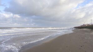 A beach with a long pier extending into the sea, a sandy shore, and a cloudy sky. - Bryn Awel (Denbigh)