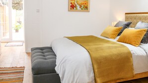 Un dormitorio con cama, almohadas, un cuadro y un banco.