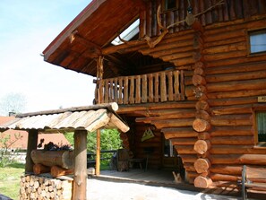 A log cabin with a balcony, a wooden deck, and a chimney.