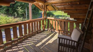 Een houten terras met een balustrade, een bank en een dakraam.