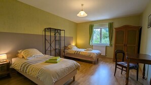 A bedroom with two beds, a desk, a chair, a hanging light fixture, and a window with curtains. - Spacious Gîte: Fireplace, Terrace, Near Epinal & Gérardmer, Sleeps 5 (Docelles)