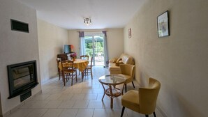 A spacious living area with a fireplace, a dining table with chairs, a sofa, and a coffee table. - Spacious Gîte: Fireplace, Terrace, Near Epinal & Gérardmer, Sleeps 5 (Docelles)