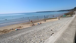 A beach with pebbles, a clear sky, and calm water. - Oakland Cottage (Narberth)