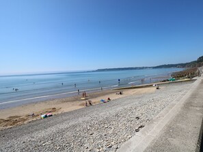 A beach with pebbles, a clear sky, and calm water. - Oakland Cottage (Narberth)