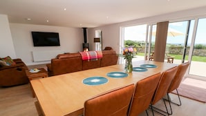Un espace repas moderne avec une table en bois, des chaises en cuir et une grande fenêtre donnant sur l’extérieur.
