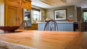 A modern kitchen with wooden cabinets, a central island, and recessed ceiling lights. - Yew Tree (Penrith)