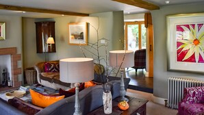 A cozy living room with a sofa, a coffee table, and a fireplace. There is a framed picture on the wall and a window providing natural light. - Yew Tree (Penrith)