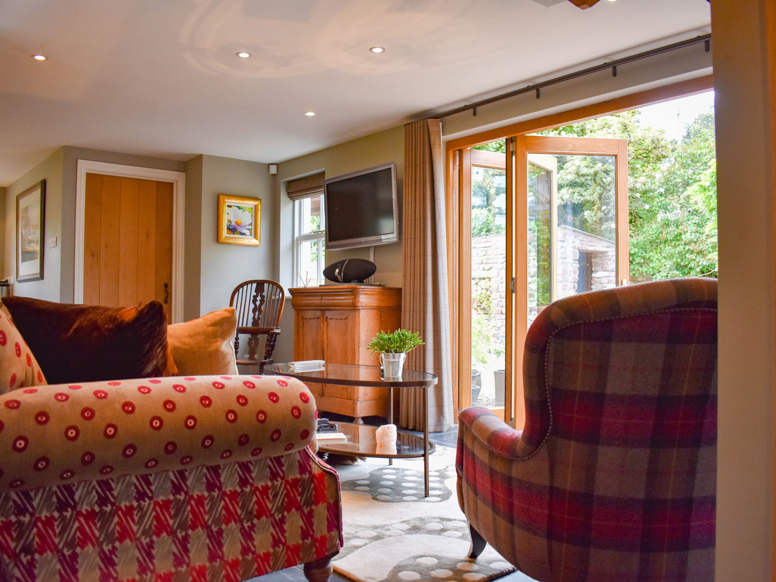 A living room with a sofa, armchair, wooden cabinet, and a television.