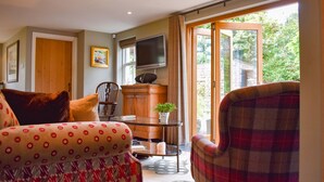 A living room with a sofa, armchair, wooden cabinet, and a television. - Yew Tree (Penrith)