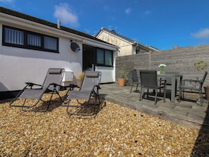 A patio with outdoor furniture, a white building, and a wooden fence.