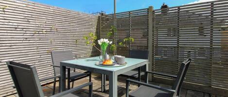 A patio with a table and chairs, a metal fence, and a street lamp.