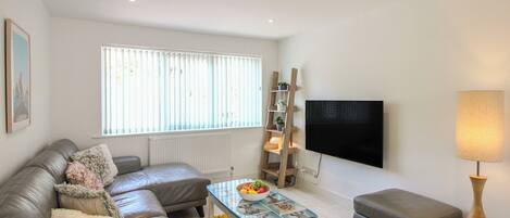 A modern living room with a sofa, a coffee table, a TV, and a lamp.